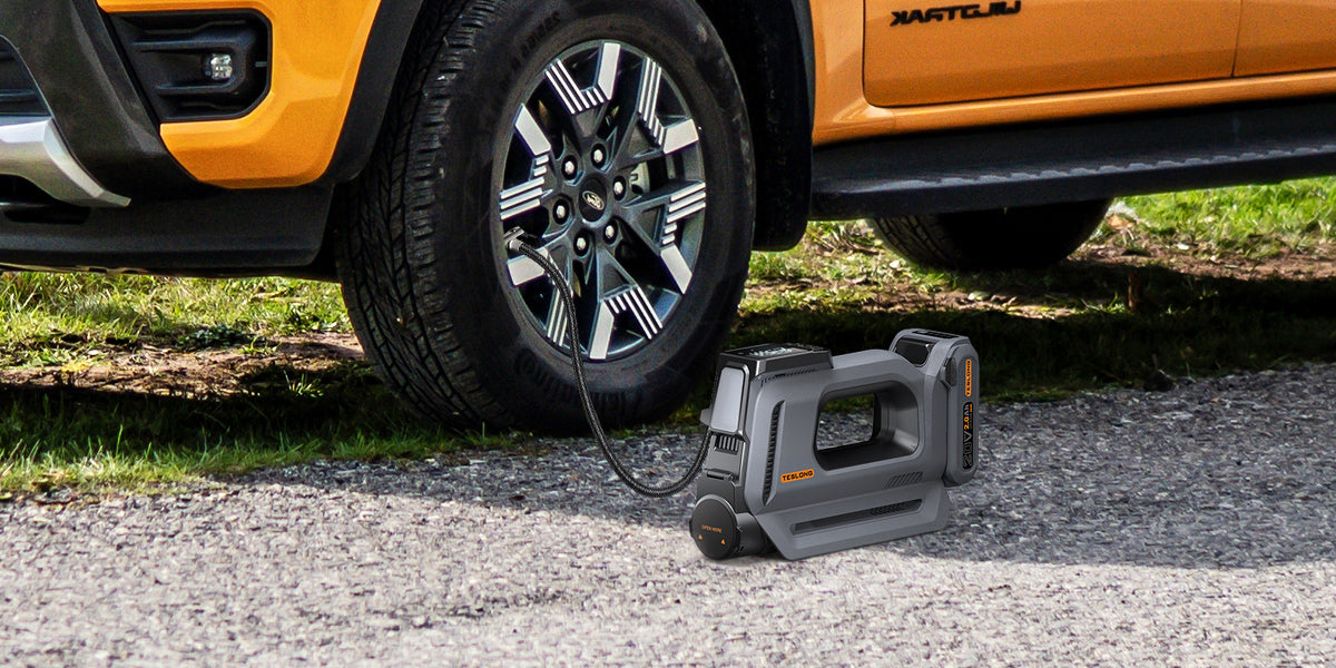 Portable tire inflator beside an orange pickup truck, connected to the front tire on a gravel road