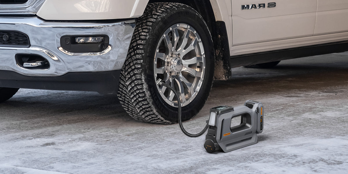Rechargeable cordless tire inflator filling a pickup truck tire in a garage