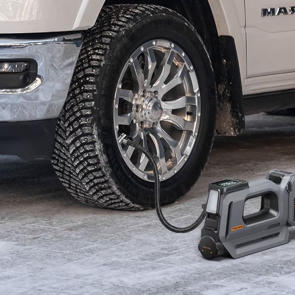 Rechargeable cordless tire inflator filling a pickup truck tire in a garage