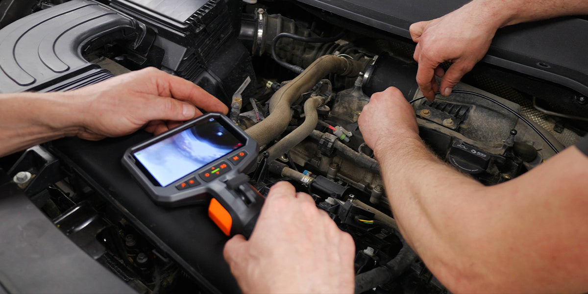 Mechanic using an automotive inspection camera to diagnose a vehicle engine problem