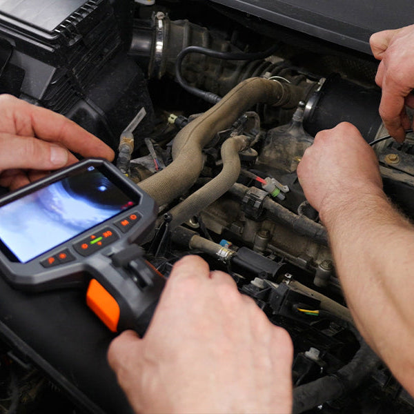 Mechanic using an automotive inspection camera to diagnose a vehicle engine problem