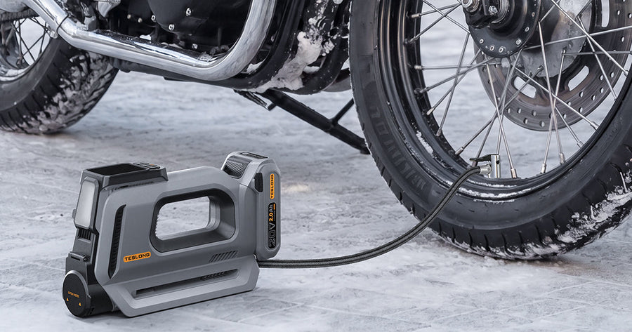 Portable cordless tire inflator pumping a motorcycle tire on a snowy road