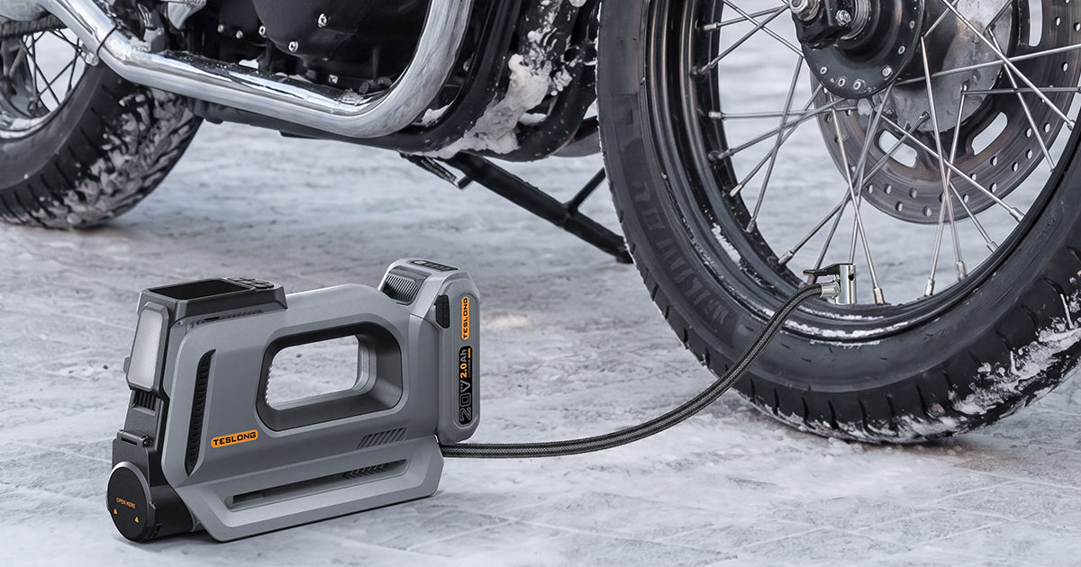 Portable cordless tire inflator pumping a motorcycle tire on a snowy road