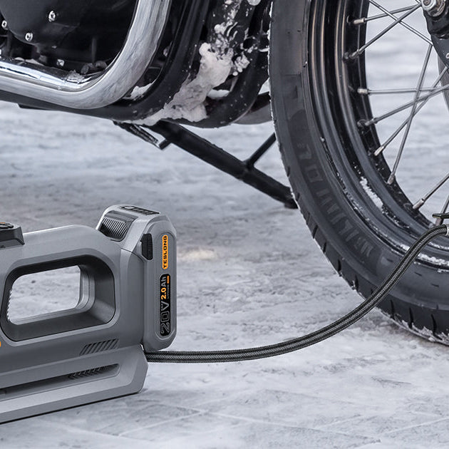 Portable cordless tire inflator pumping a motorcycle tire on a snowy road
