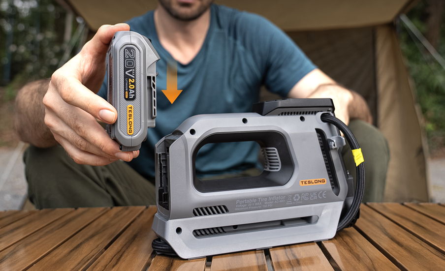 Man inserting a 20V lithium battery into a portable tire inflator at a campsite