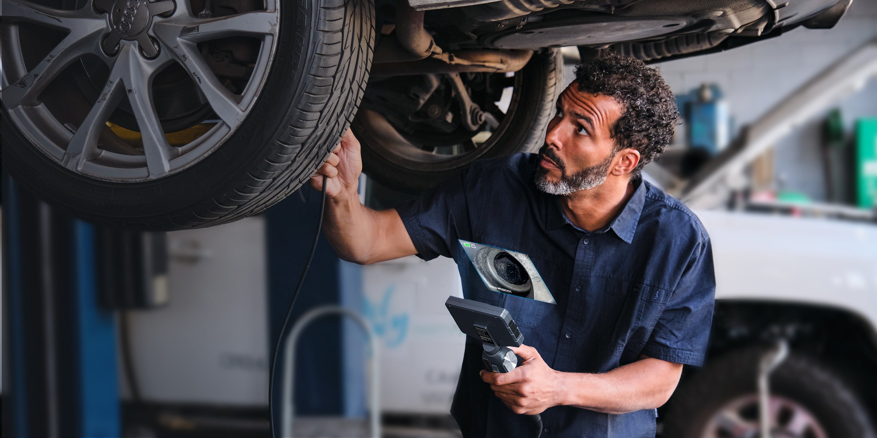 Mechanic using a Teslong inspection camera beneath a vehicle